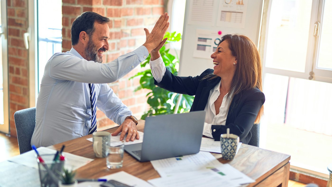 Two colleagues celebrating at a desk